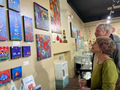 <p>This couple caught admiring Marna Schindler’s colorful artwork! They said they have at least 6 of her pieces already!!</p>